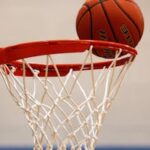 A basketball moment captured as the ball rests on the rim, highlighting the suspense of the game.