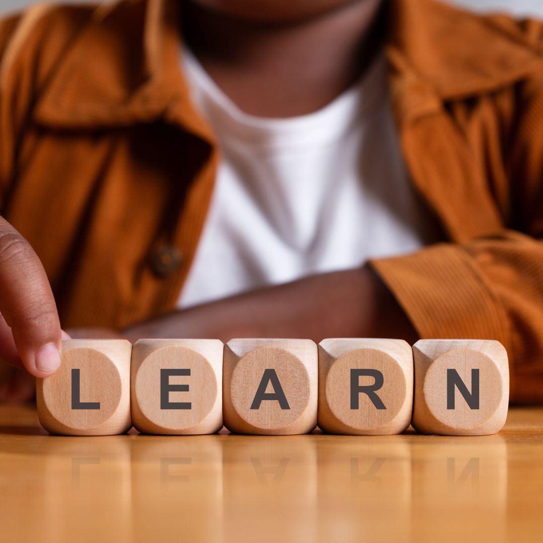 A group of young adults laughing and enjoying time together outdoors under the sun.