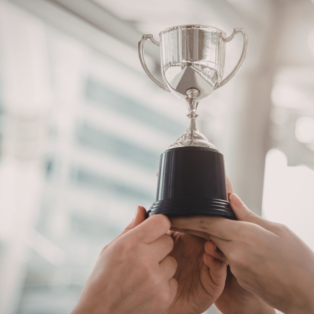 A group of young adults laughing and enjoying time together outdoors under the sun.